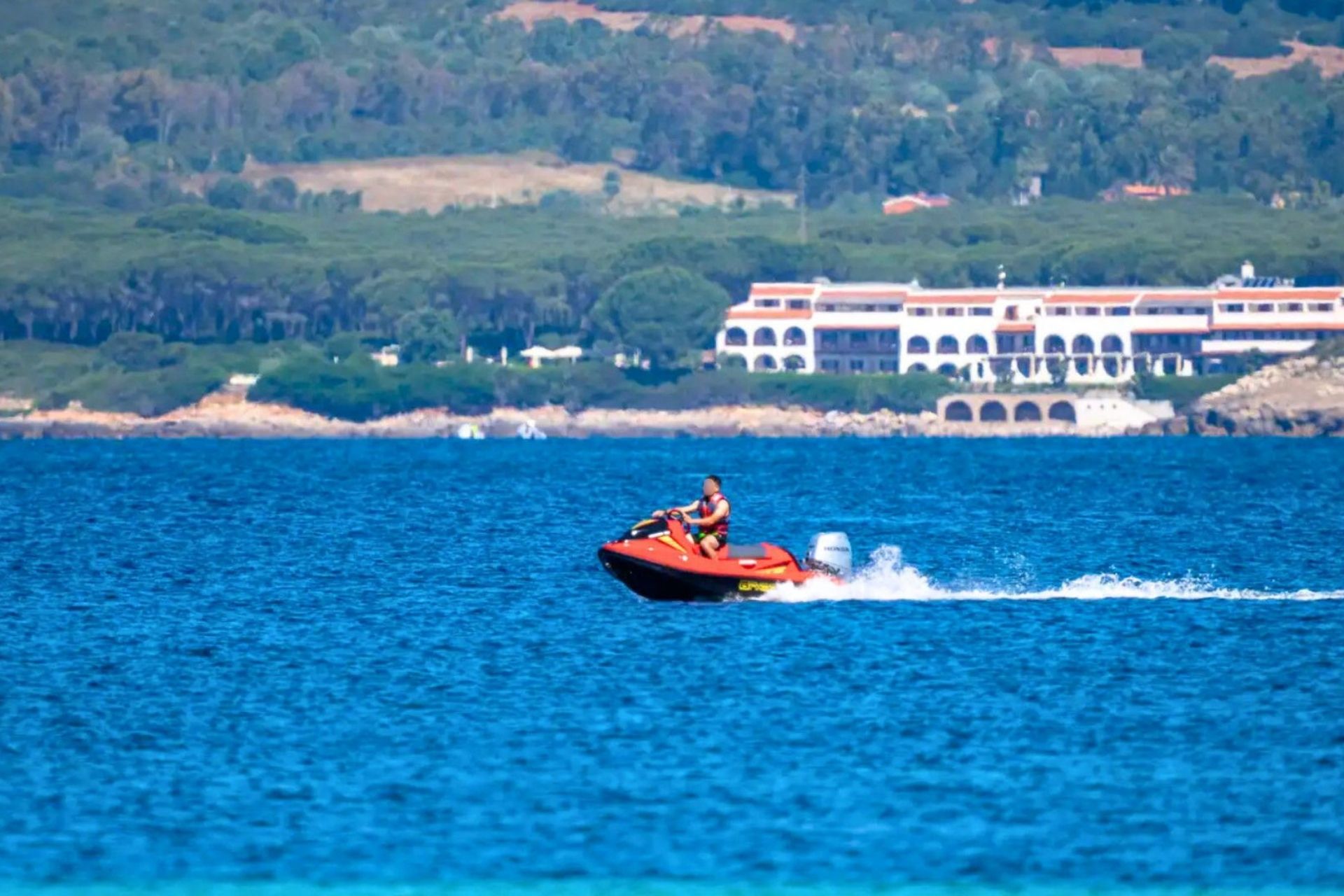 Una persona in sella a una moto d'acqua sfreccia sul mare azzurro