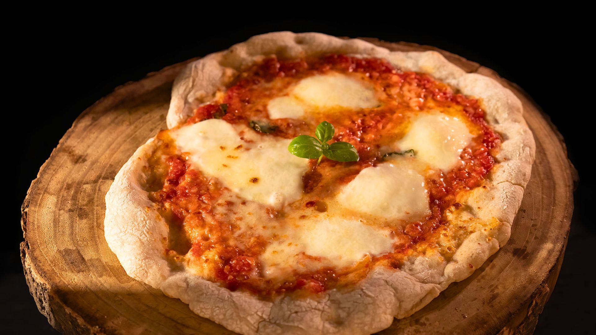 Pizza con pomodoro, mozzarella e basilico su una base di legno, pronta per essere gustata