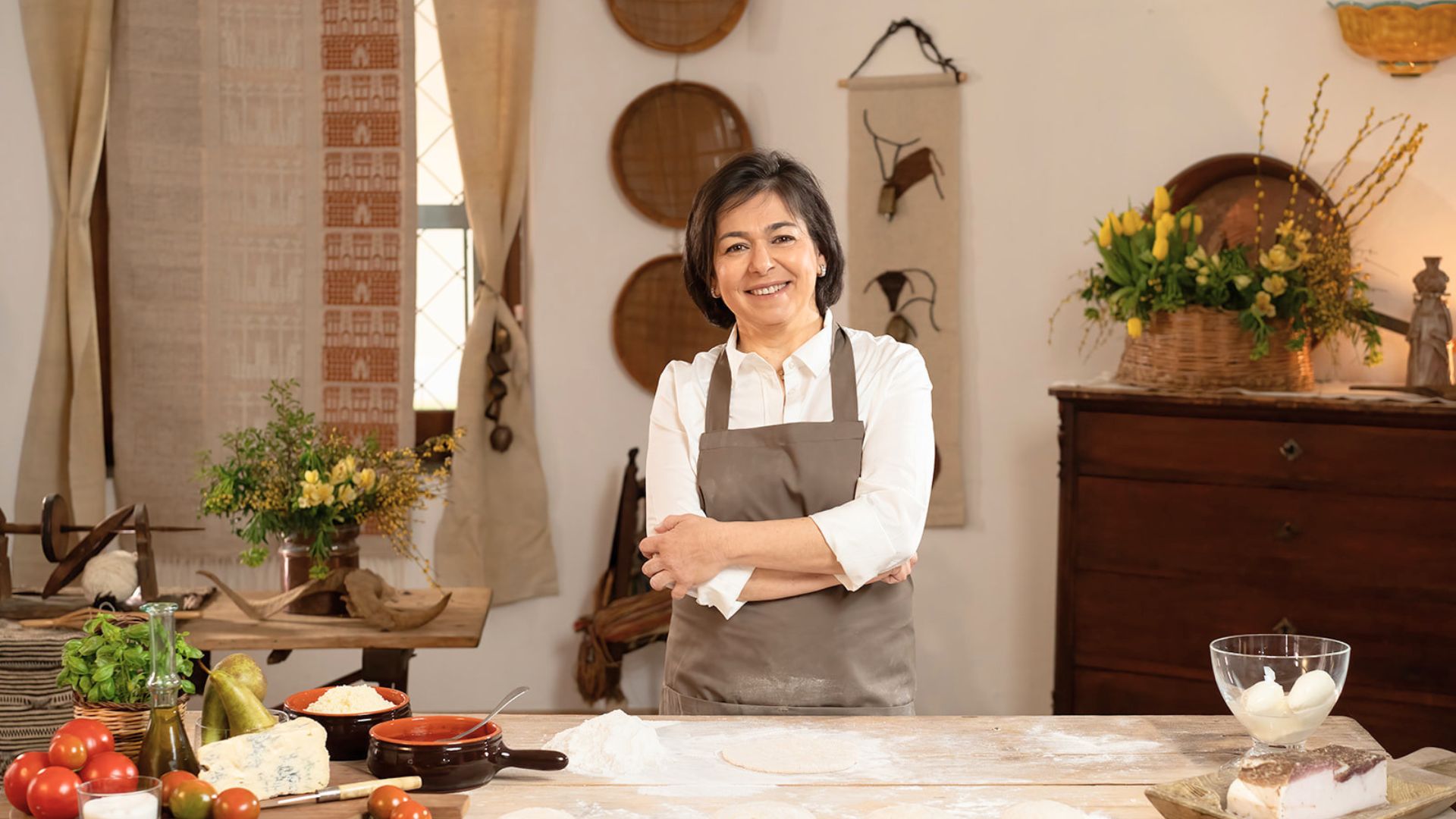 Una donna in un ambiente rustico, con ingredienti per la pizza e una tavola preparata per la cottura