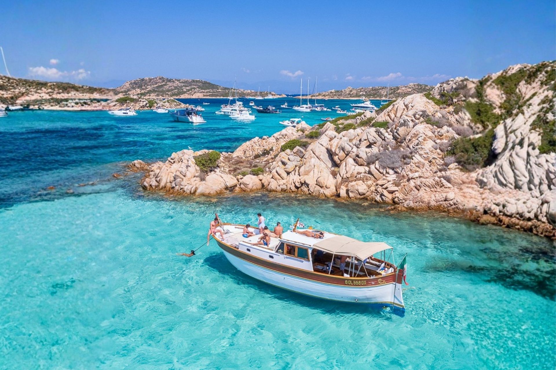A vintage boat sails between the islands of Caprera, Budelli and Spargi in the La Maddalena Archipelago, surrounded by crystal clear sea and enchanting natural landscapes.