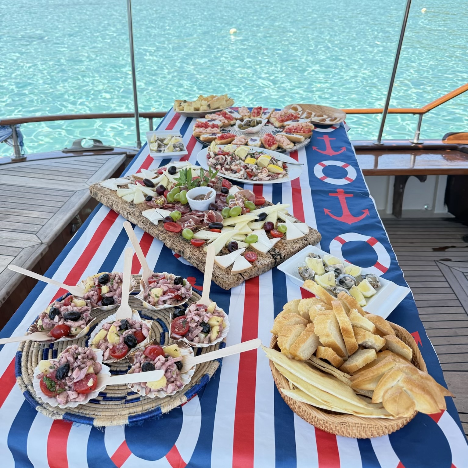 Tisch mit Essen auf einem Segelboot mit dem Meer im Hintergrund.