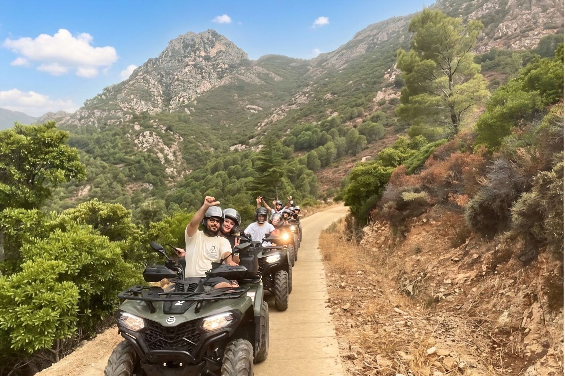 Groupe de personnes en quad sur un chemin de terre entre paysages de montagne et maquis méditerranéen