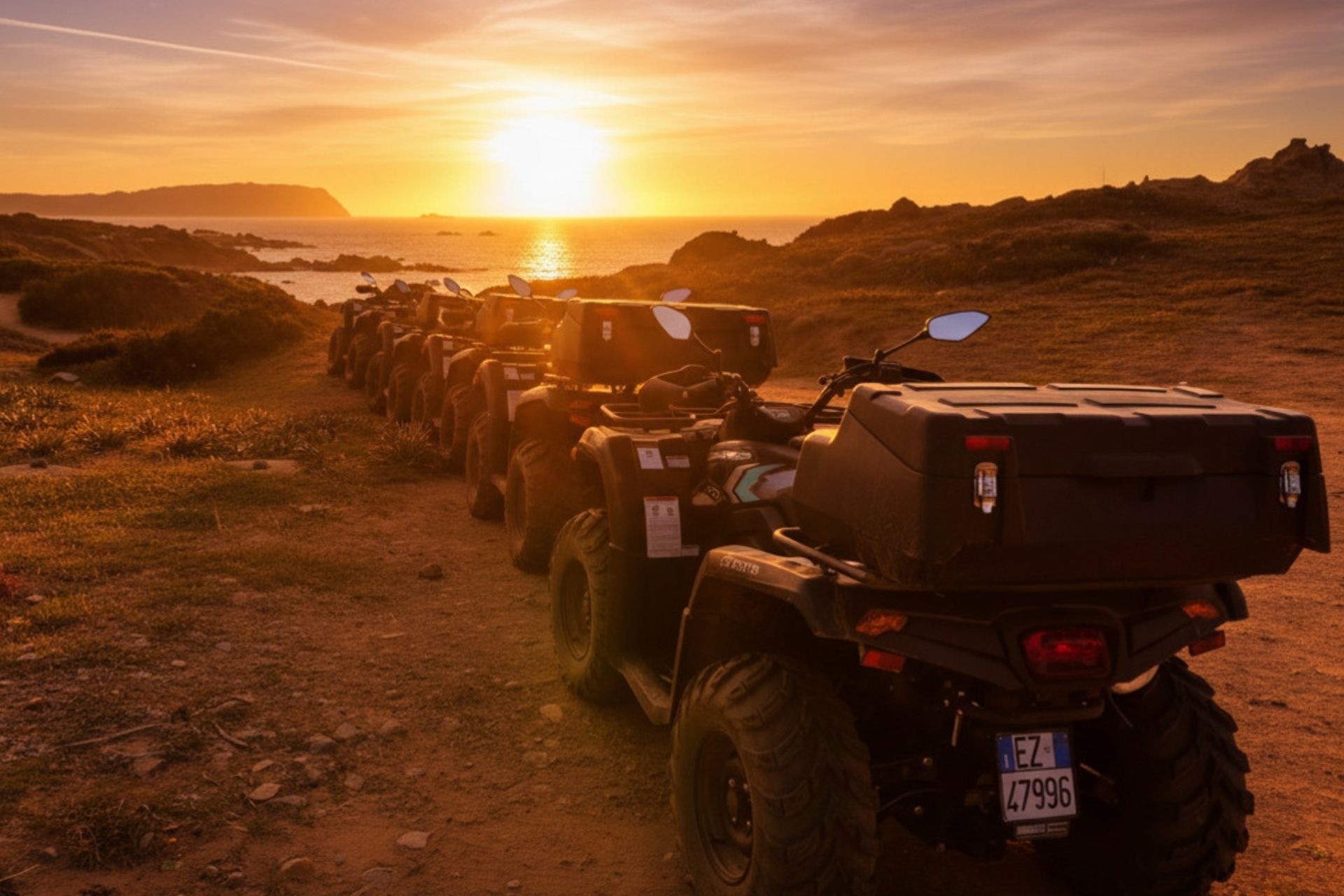 Quads garés sur un chemin de campagne avec la mer en arrière-plan au coucher du soleil