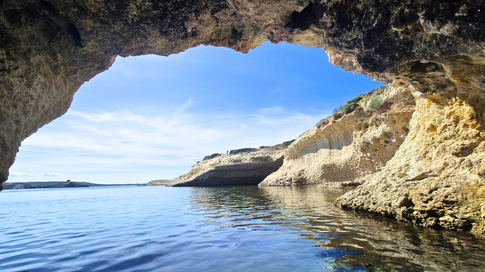 Un kayak trasparente naviga tra calette nascoste e scogliere modellate dal vento, con vista sui fondali marini