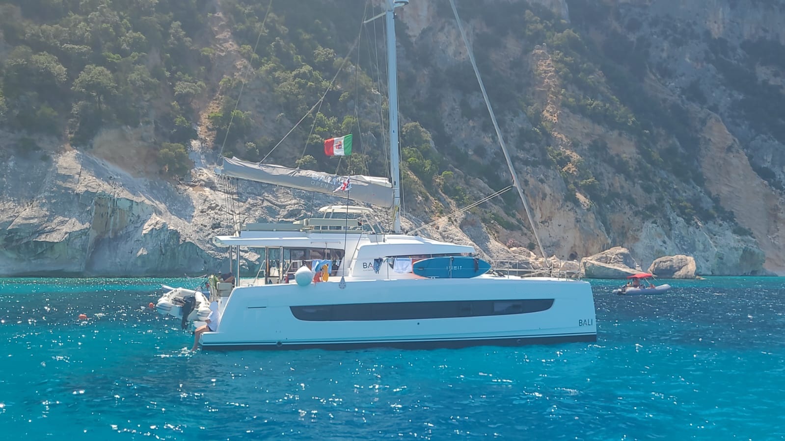 Catamarán amarrado en una bahía con acantilados de granito y aguas cristalinas.