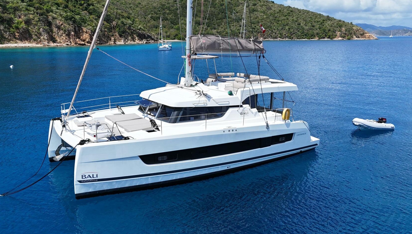 Catamarán Bali 4.5 amarrado en aguas cristalinas con acantilados de granito al fondo