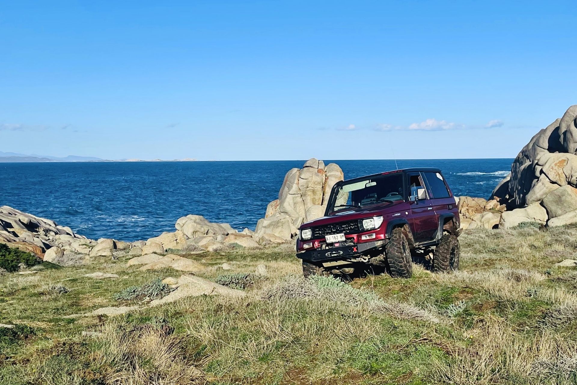 An off-road vehicle navigates wild and uncontaminated landscapes, granite hills and natural trails, with panoramic views of the Maddalena Archipelago.
