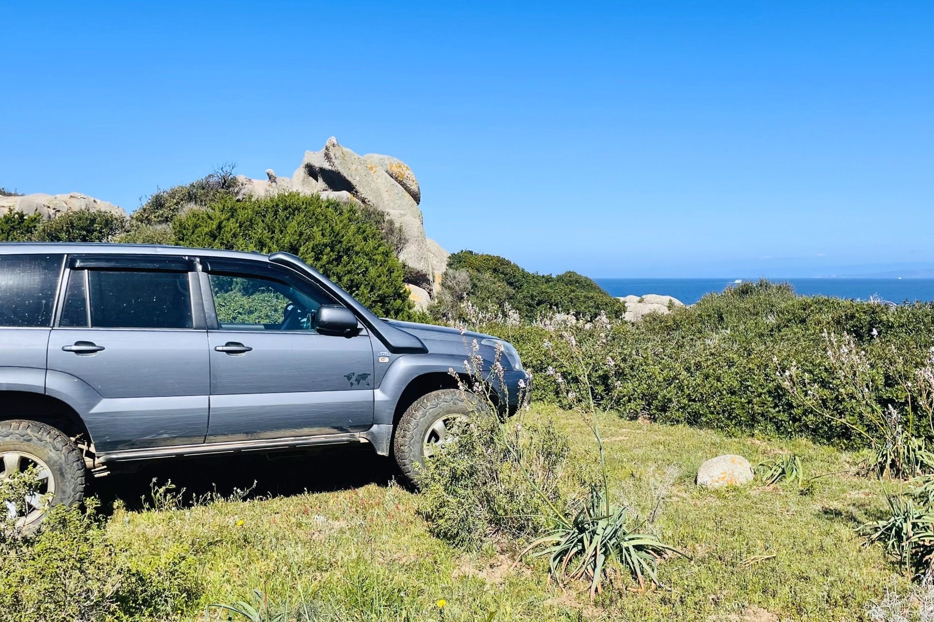 An off-road vehicle crosses granite landscapes and Mediterranean scrub, with views of the Maddalena Archipelago and the possibility of swimming in Rena Bianca.