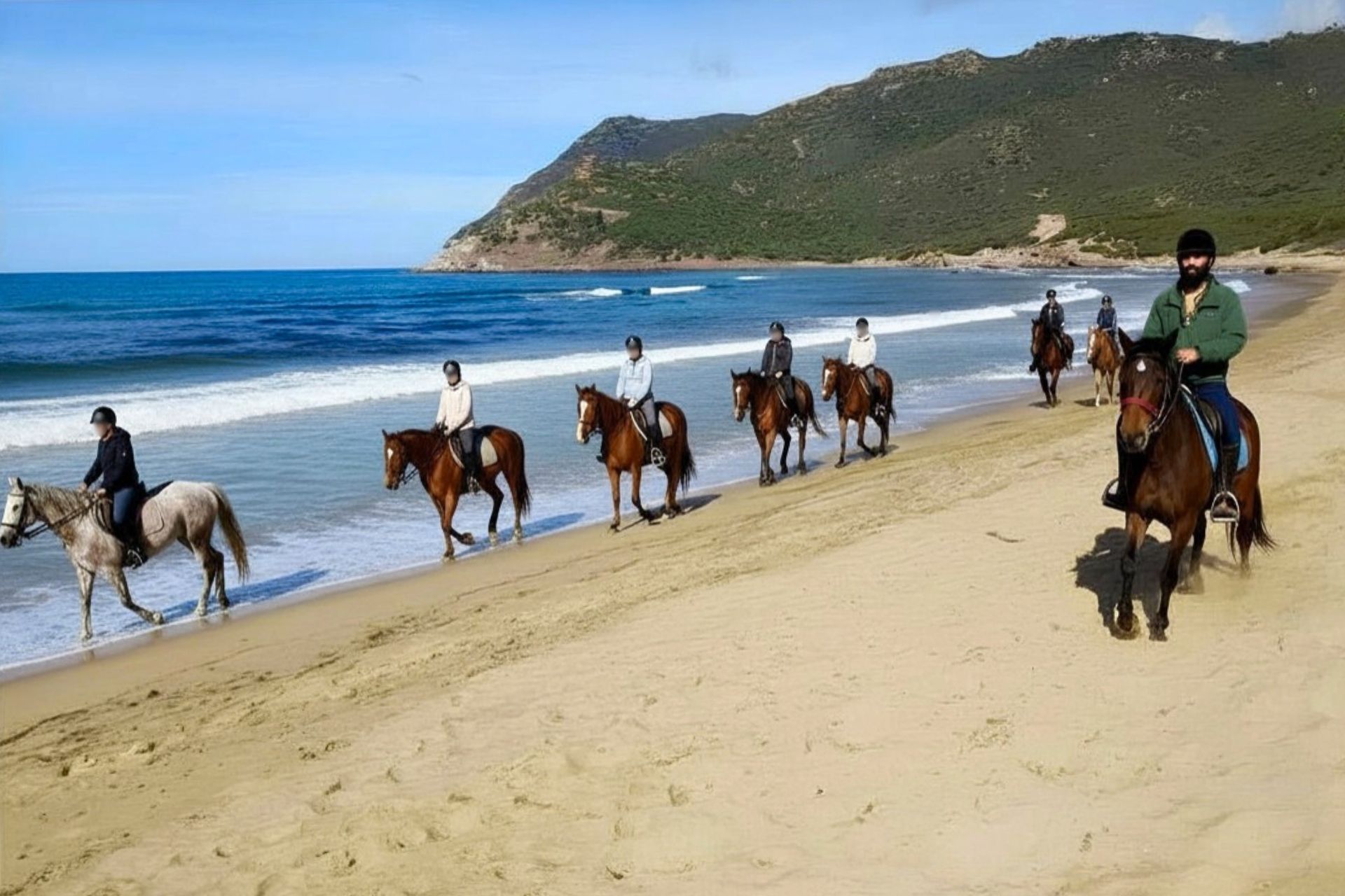 Un gruppo di persone cavalca lungo la spiaggia di Porto Ferro
