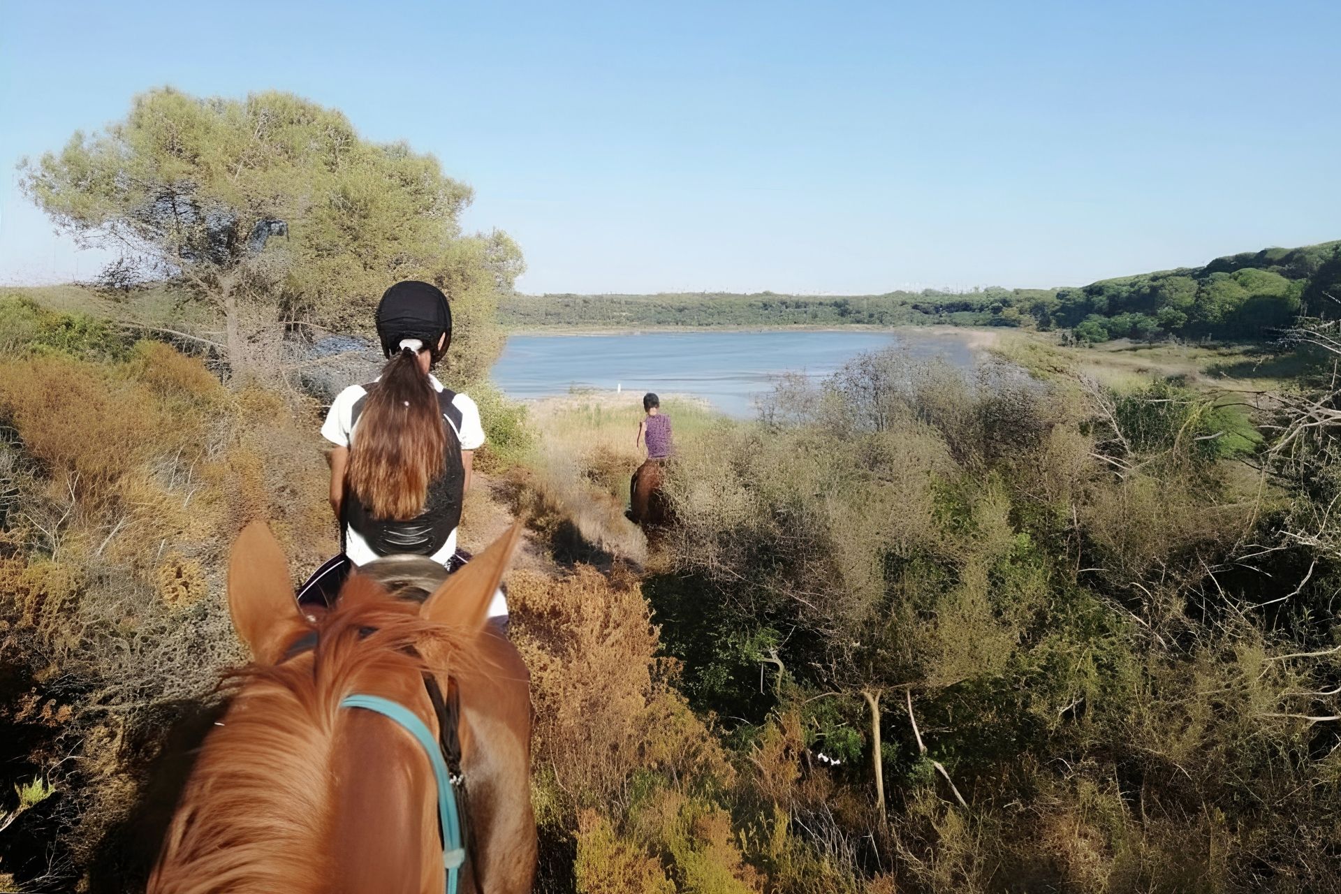 Due persone a cavallo arrivano nel paesaggio naturale del lago di Baratz