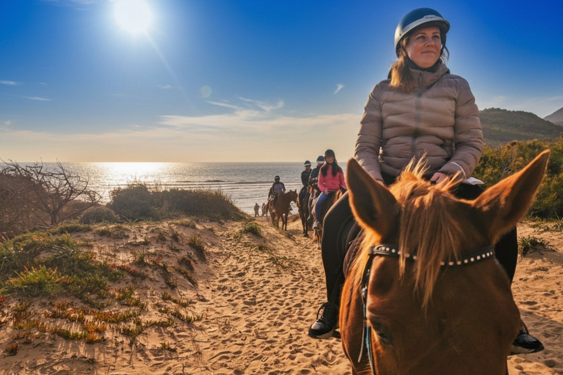Una donna cavalca un cavallo lungo una spiaggia sabbiosa con vista sul mare
