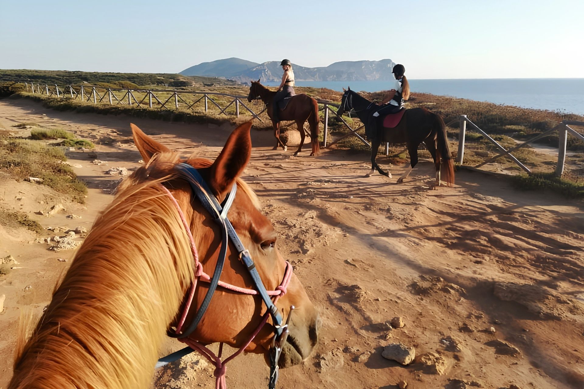 Deux cavaliers expérimentés à cheval sur un chemin de terre devant Porto Ferro