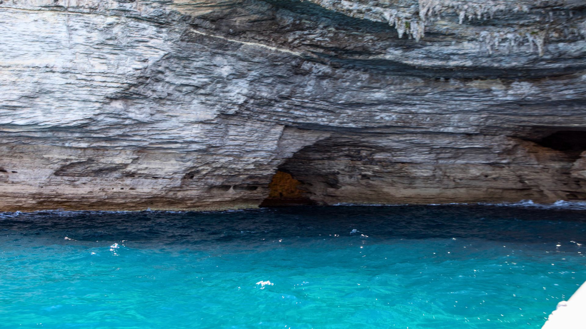 Immagine di un mare cristallino con una grotta di roccia sulla sinistra, ideale per un'avventura di noleggio gommone