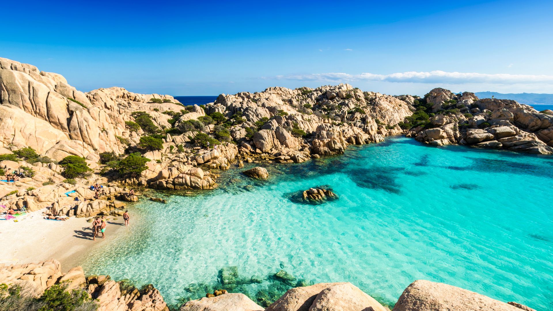 Un gruppo di persone si gode la spiaggia di un'isola con scogliere granitiche e mare cristallino