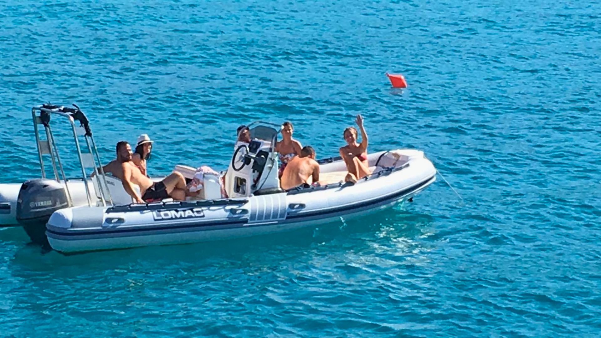 Un gruppo di persone in un gommone sul mare, circondato da acque cristalline e paesaggi pittoreschi