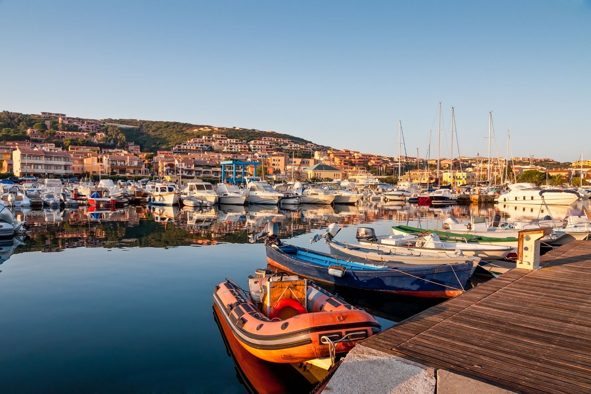 Image of a port with moored boats and an urban landscape in the background, ideal for a trip to Sardinia.