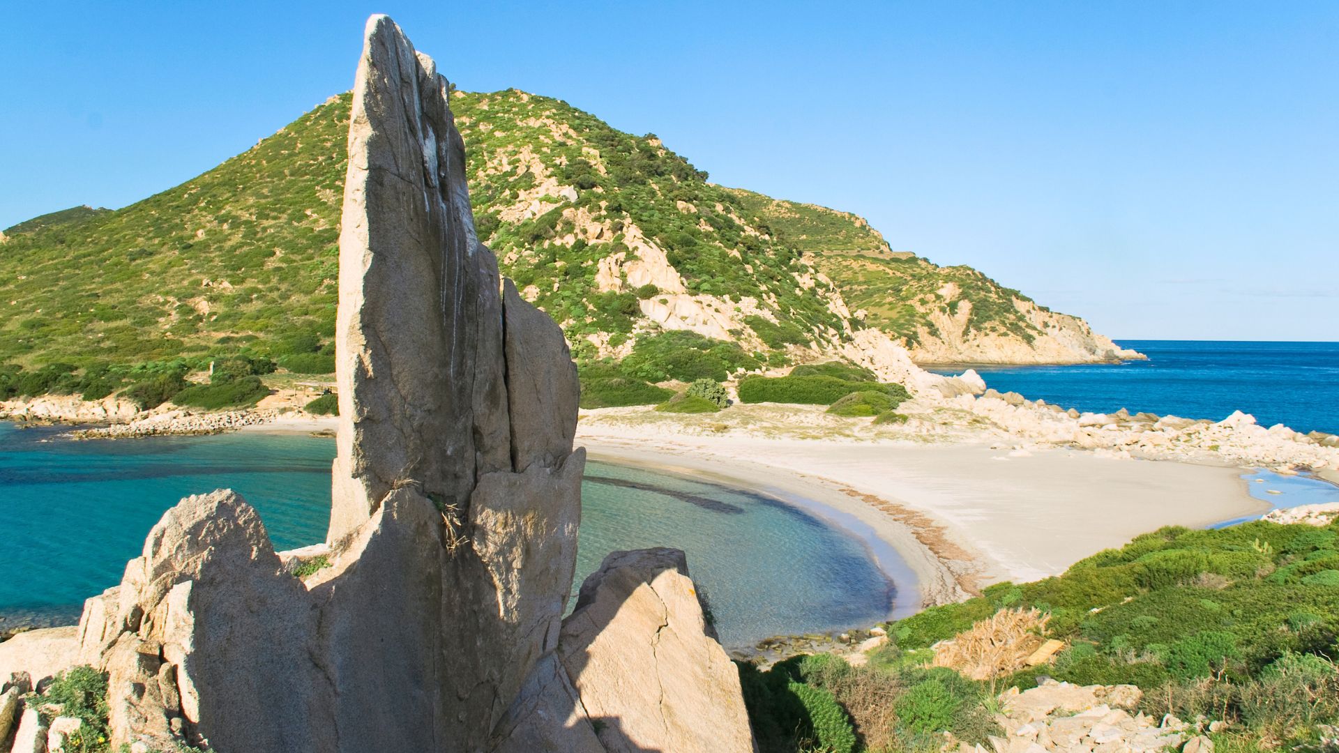 Picture of a beach with rocky cliffs and crystal clear sea, ideal for holidays in Sardinia