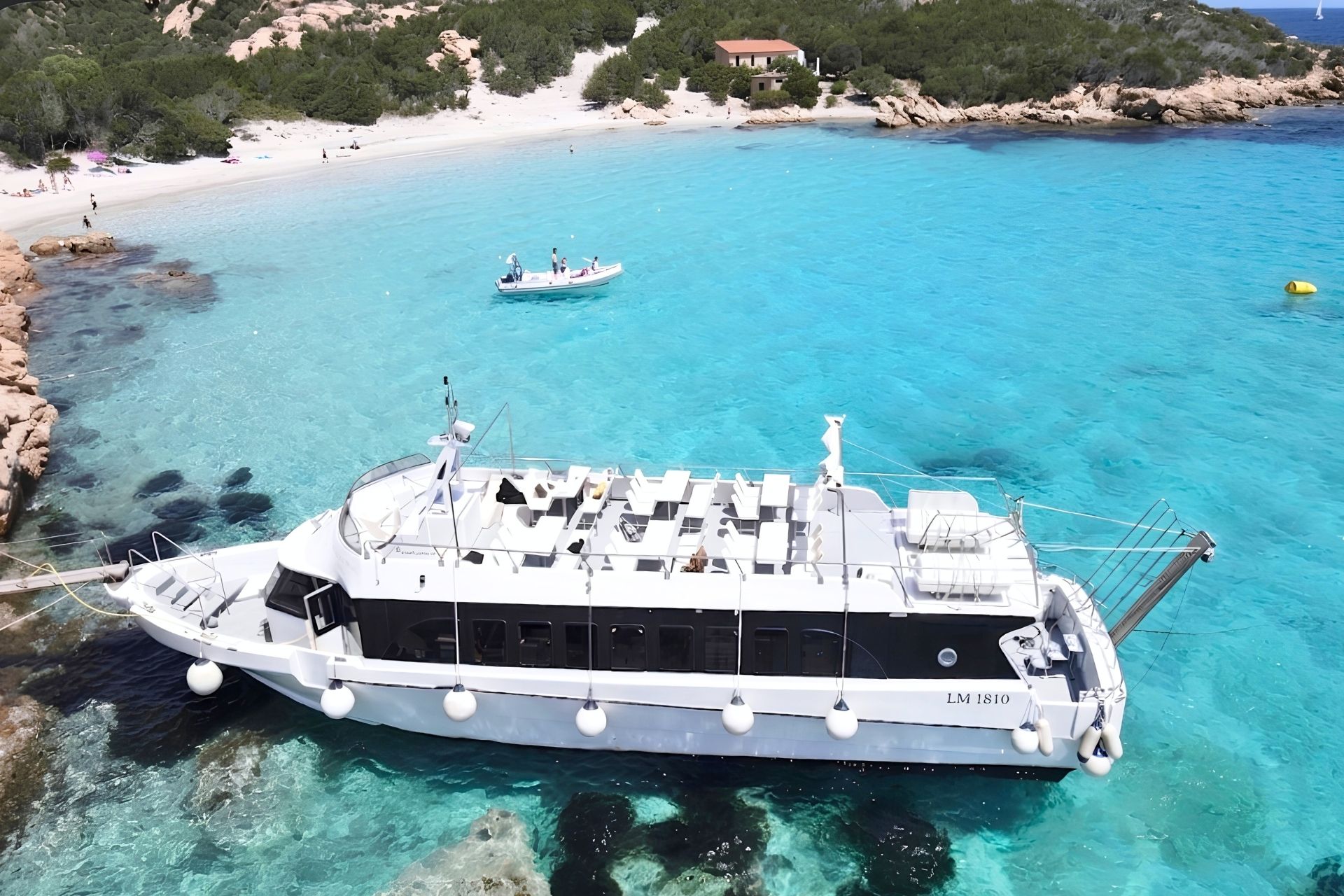 Una motonave naviga in acque turchesi con isole e spiagge bianche sullo sfondo