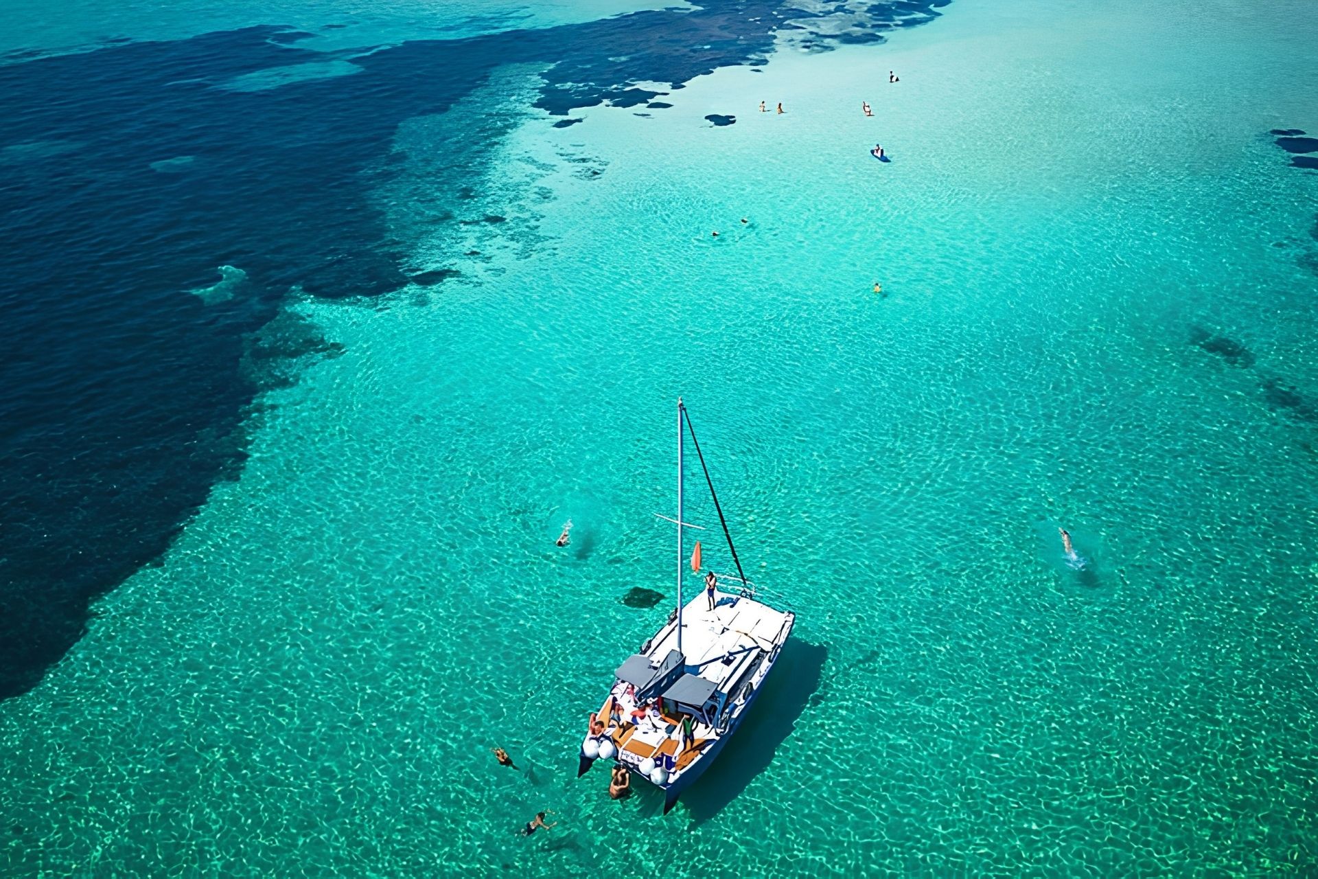 Navegación en catamarán en aguas cristalinas con personas a bordo que viajan a Asinara