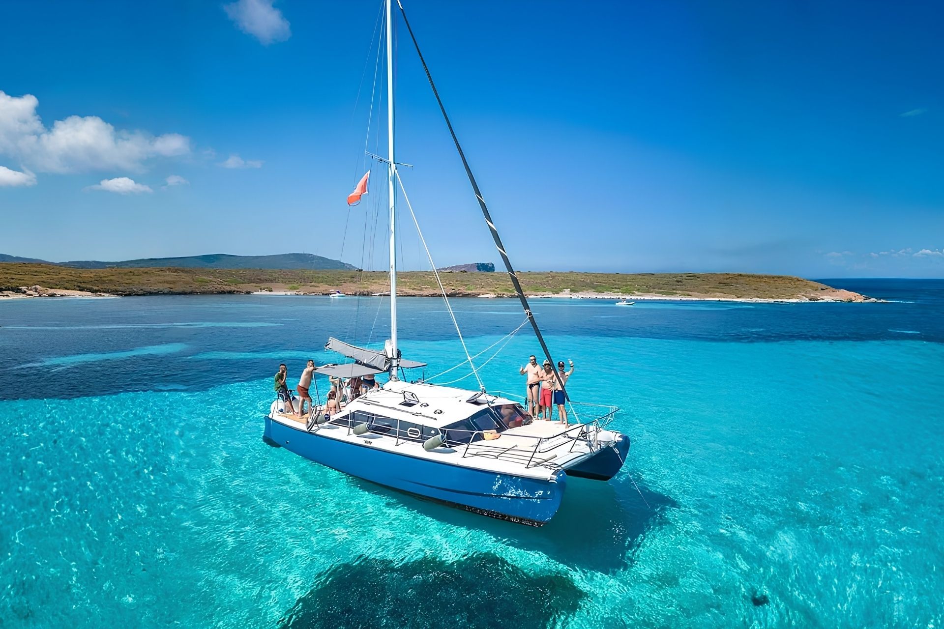 Gente en catamarán navegando por las aguas turquesas y cristalinas de Asinara