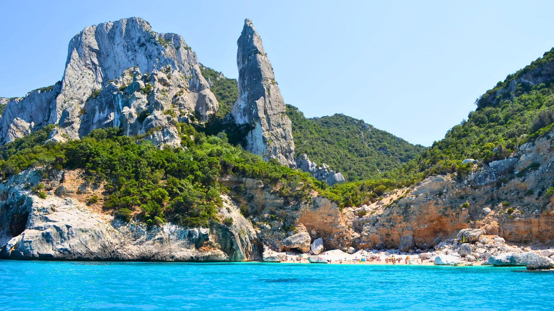 Ein Motorschiff segelt entlang der Ostküste Sardiniens, zwischen hohen Klippen und malerischen Buchten, mit Stopps am Strand und einem Besuch der Grotte del Bue Marino