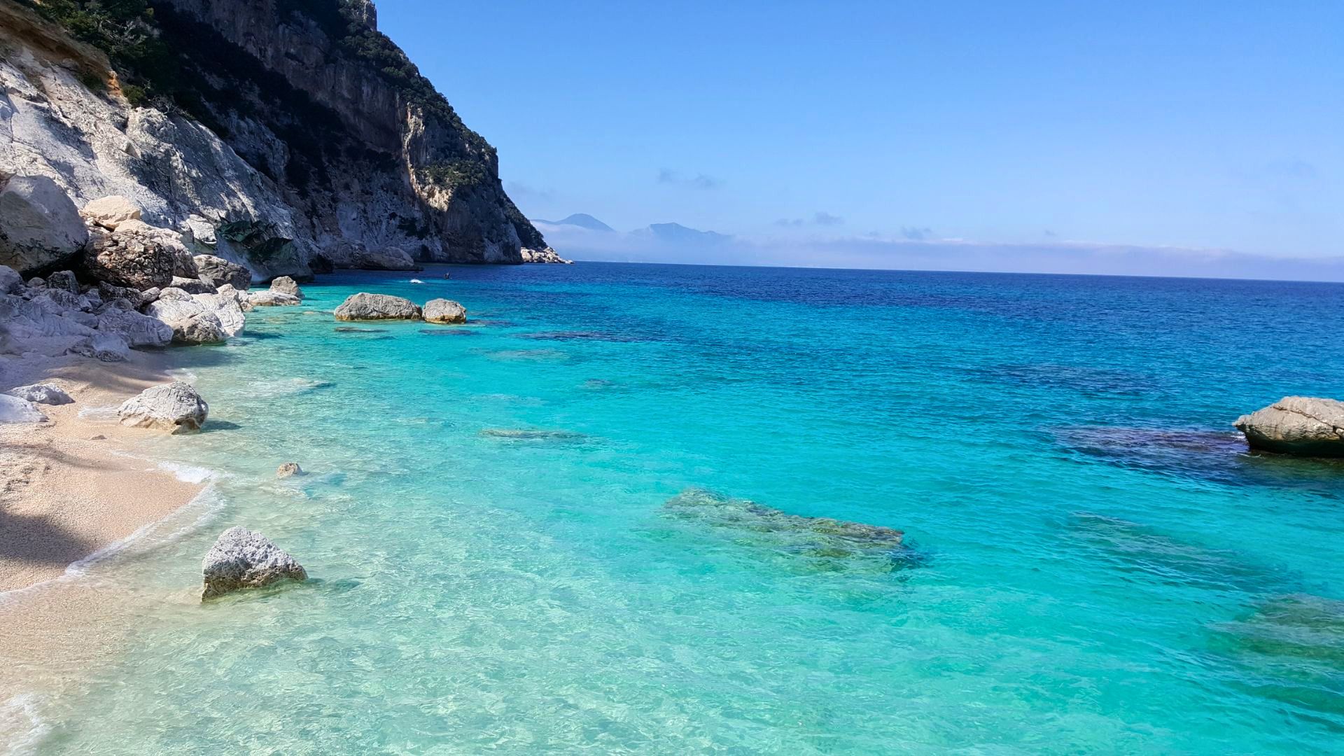 Bild einer felsigen Küste mit kristallklarem Meer und einigen Felsen im Wasser