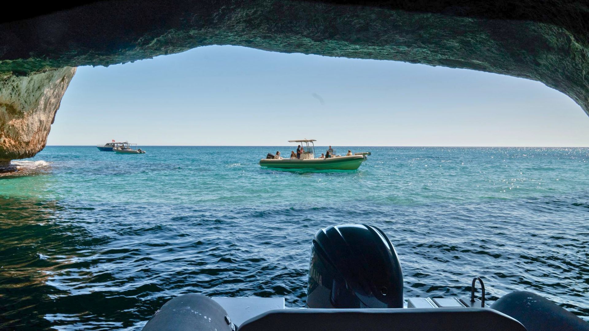 Image of a dinghy with people on board in a crystal clear sea