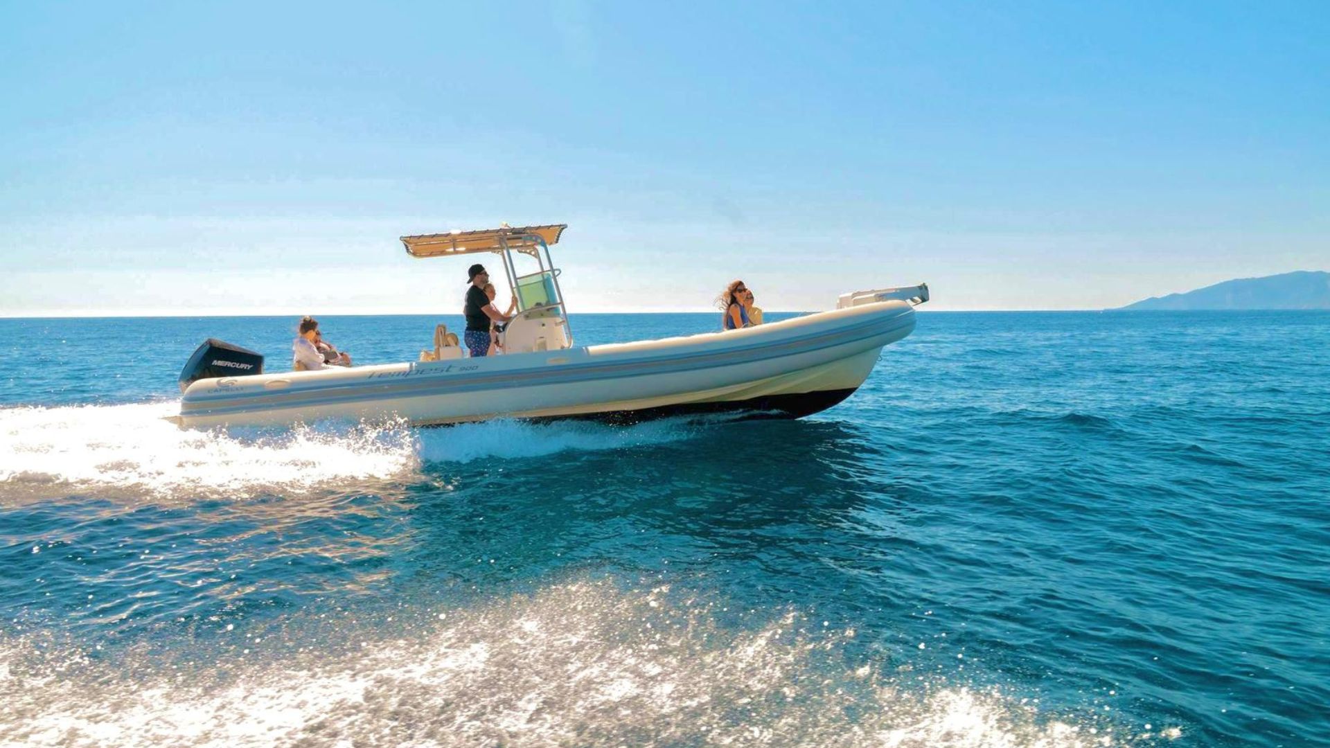A sailboat with people on board sails on the blue sea under a blue sky