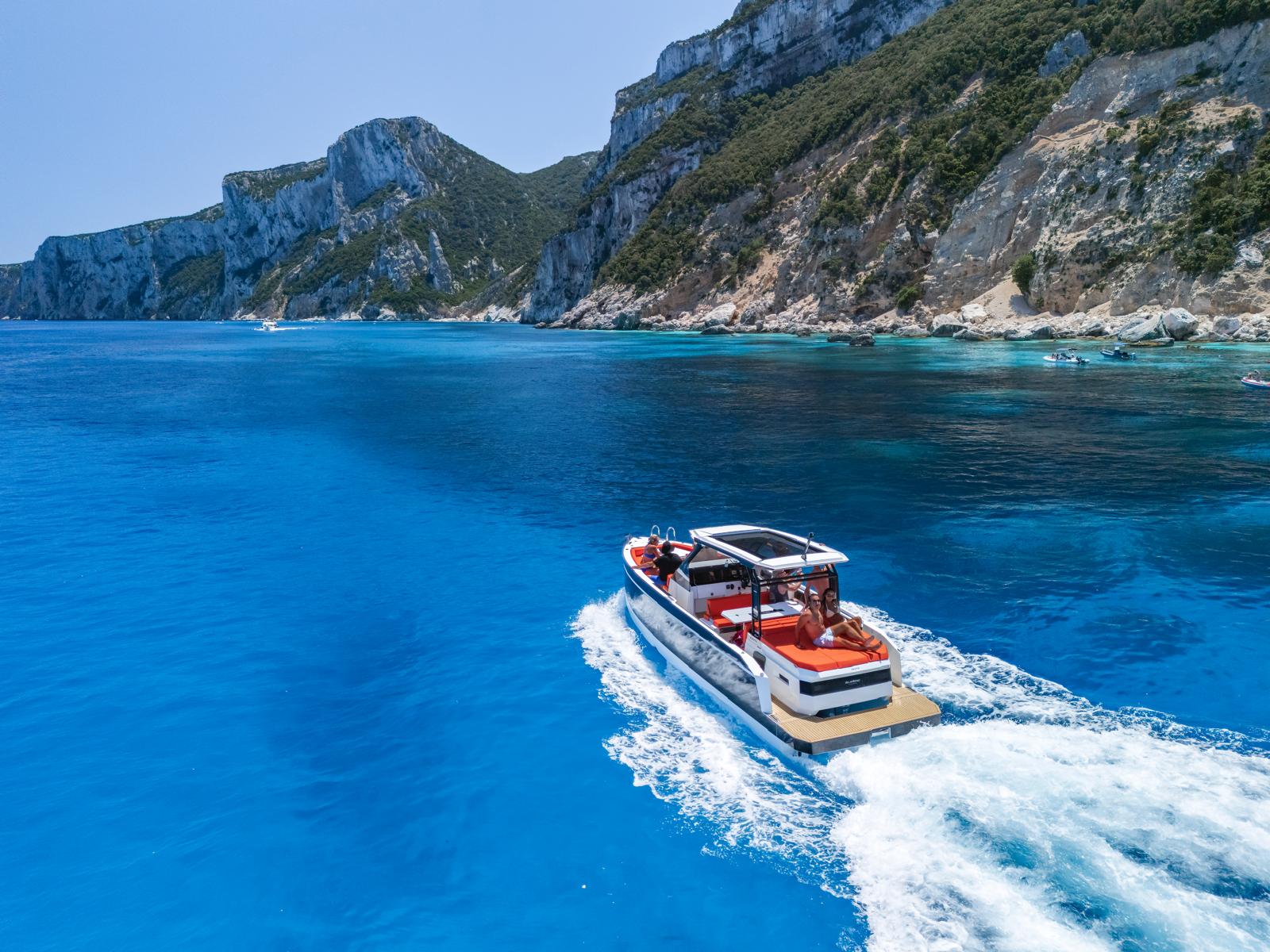 Mini yacht sailing in turquoise waters with people on board enjoying the view