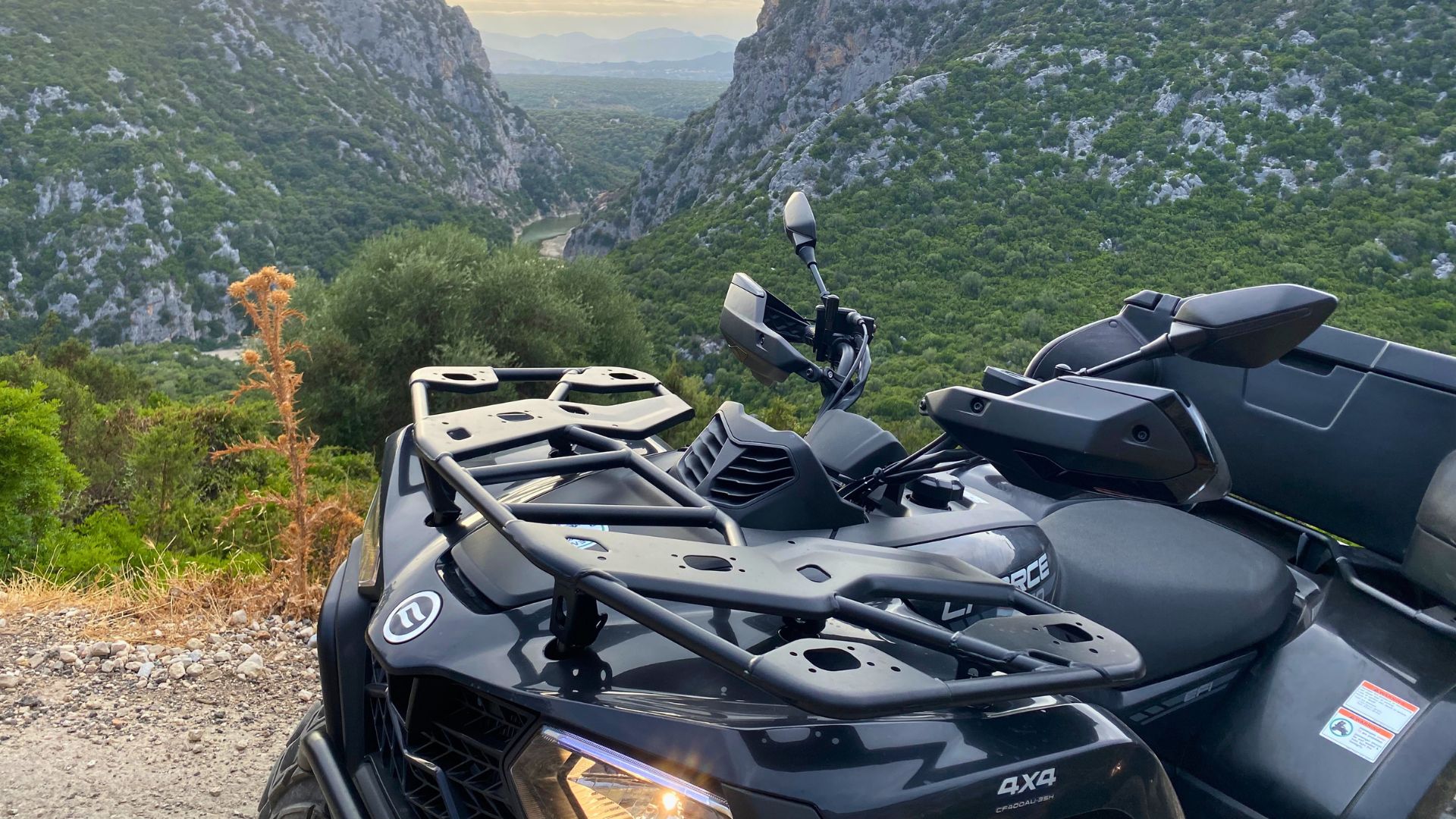 Quad nero parcheggiato su un sentiero sterrato con vista su una vallata verdeggiante e rocce calcaree
