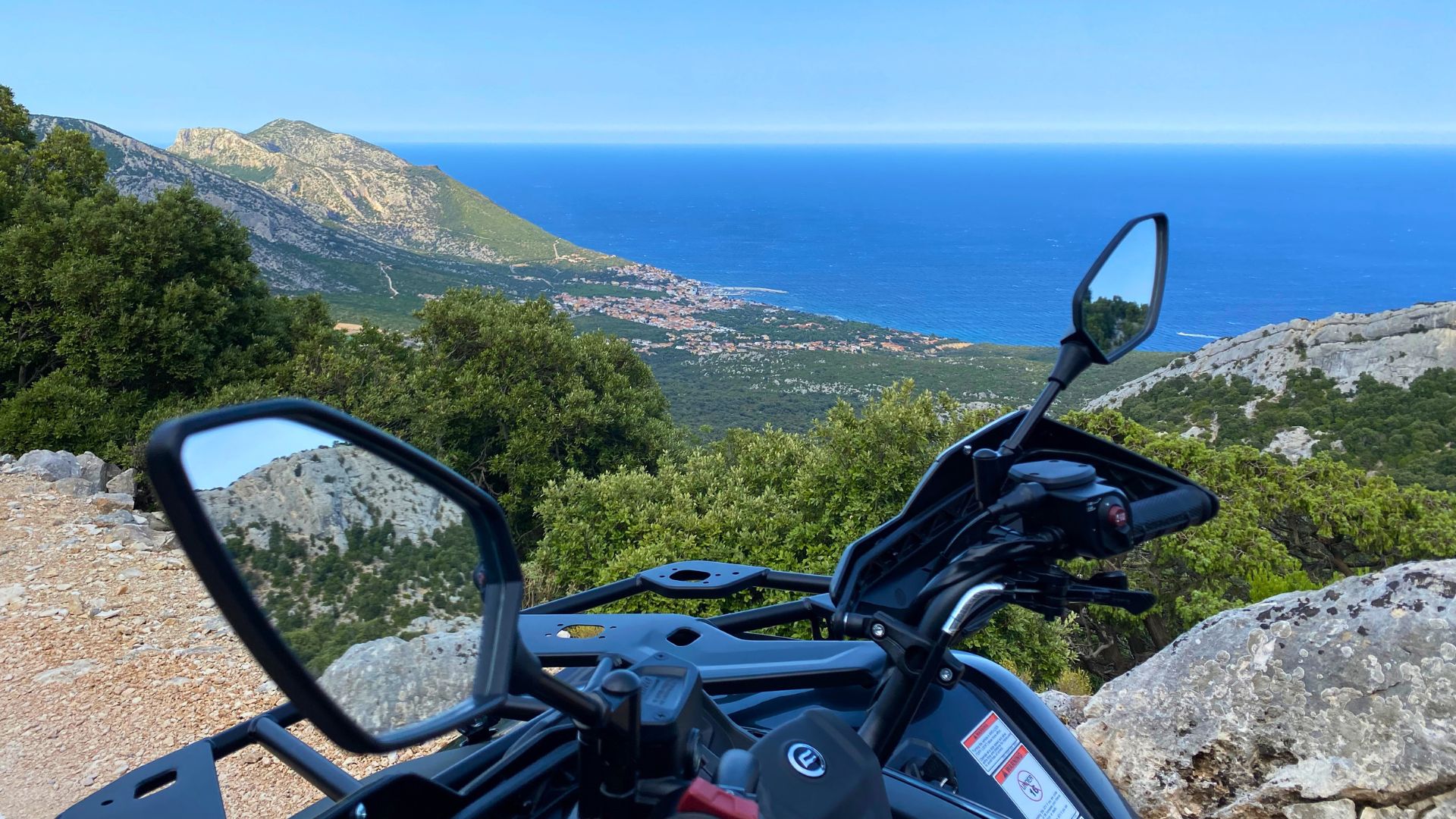 Vista panoramica di un quad su un sentiero sterrato con mare e montagne sullo sfondo