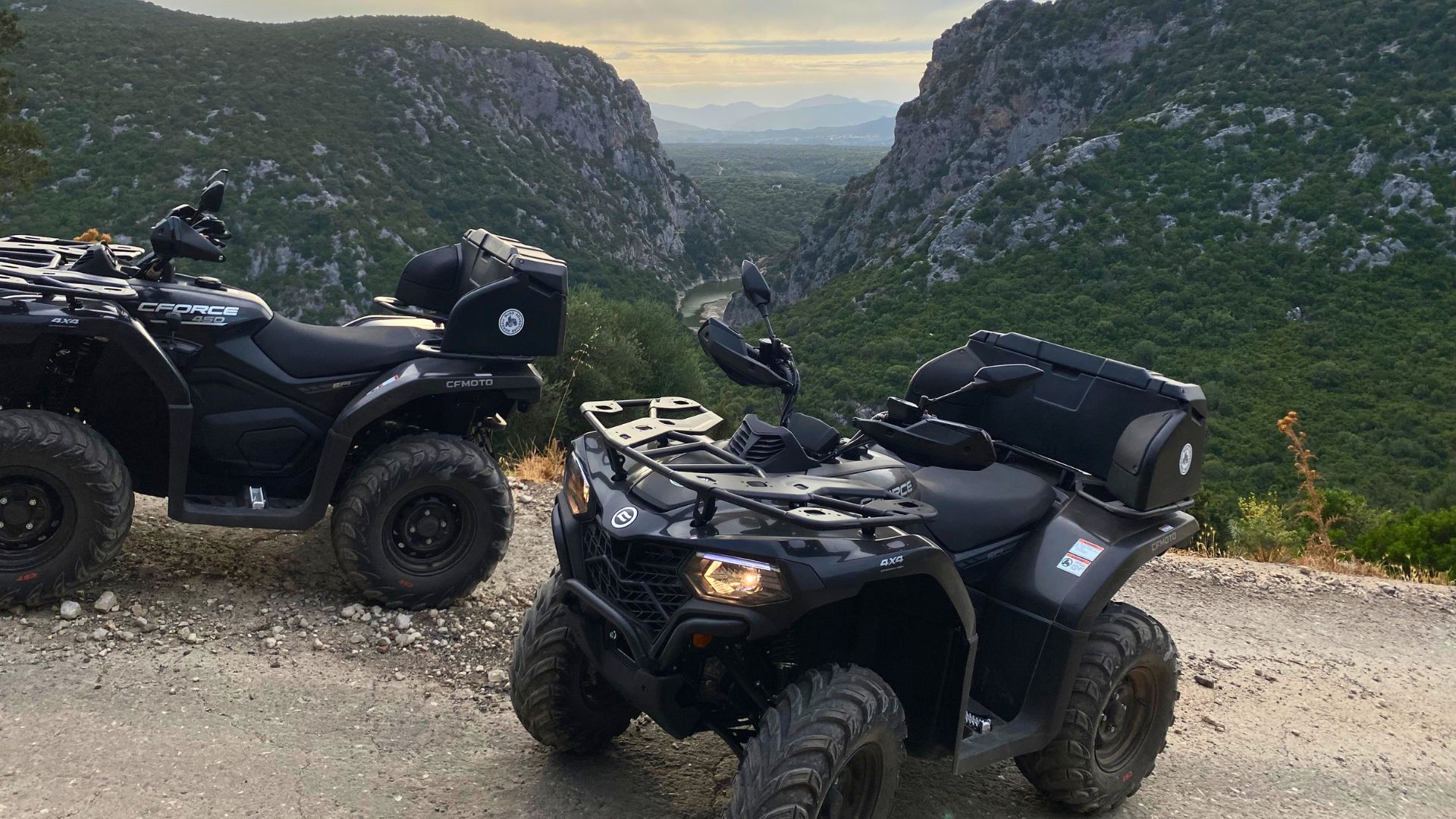 Due quad neri parcheggiati su un sentiero sterrato con vista su una vallata verdeggiante e rocce a picco sul mare