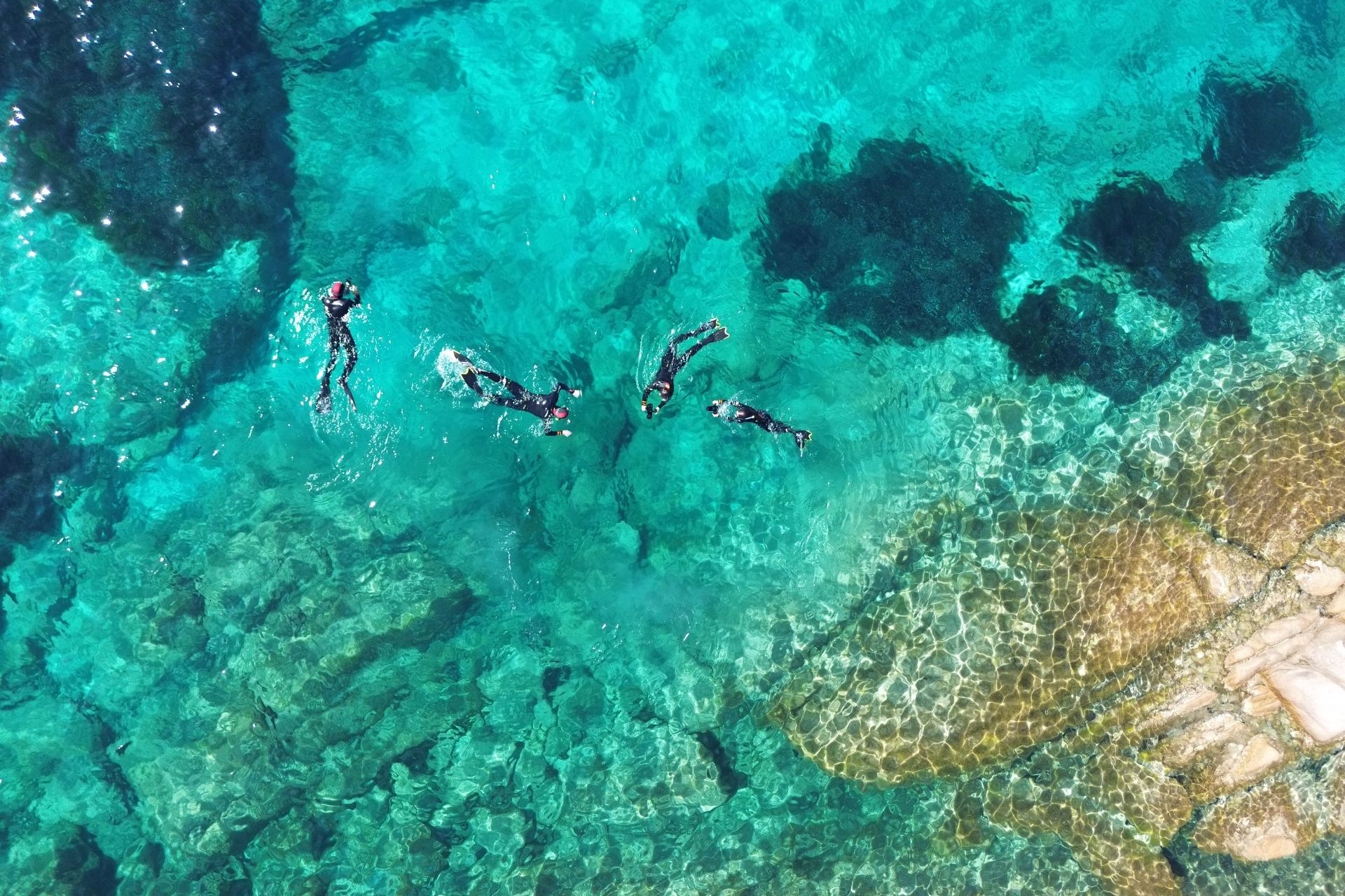 Immagine di persone che fanno snorkeling nelle acque cristalline delle Piscine di Molara, Sardegna.