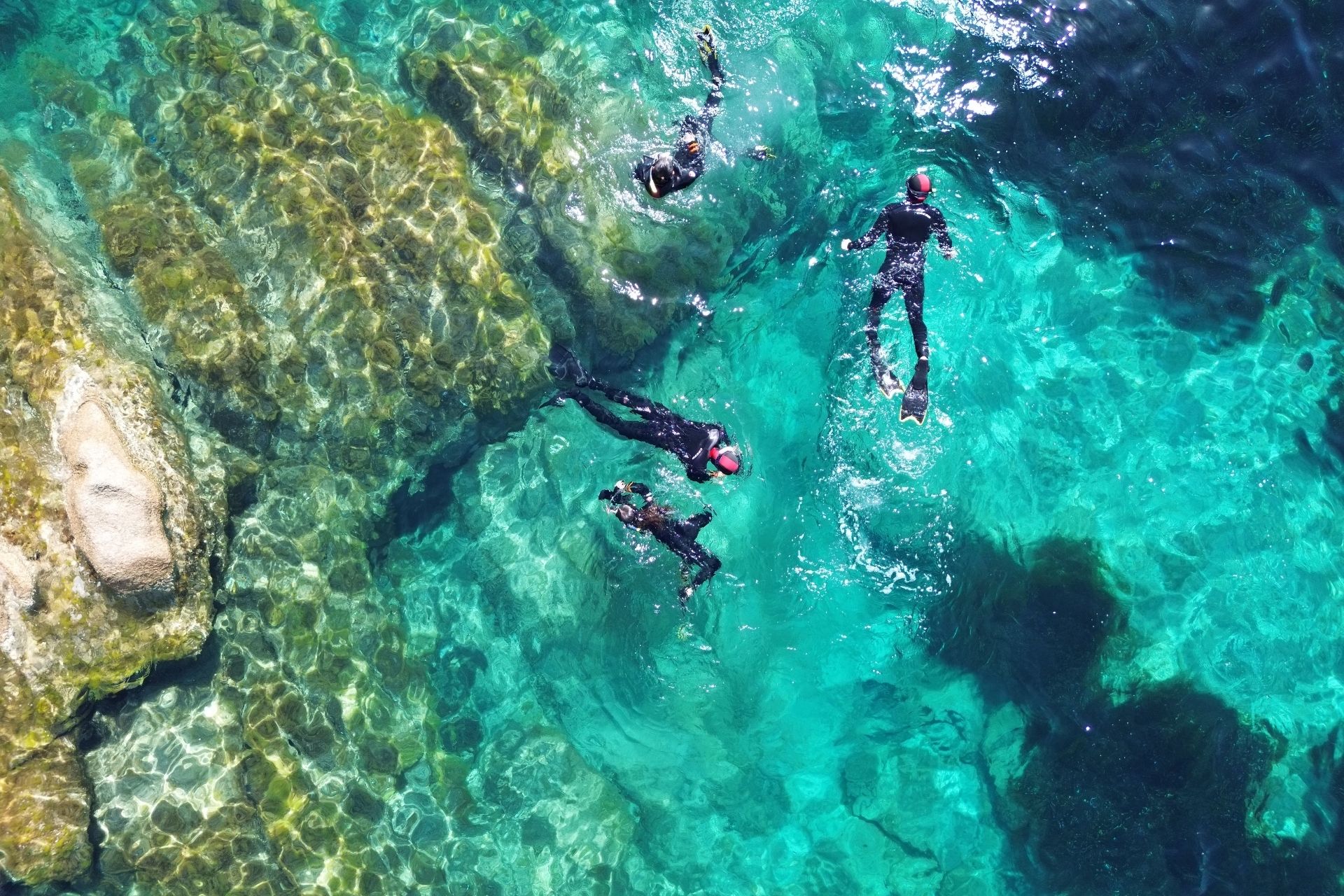 Persone che fanno snorkeling nelle acque cristalline e colorate delle Piscine Naturali di Molara, nell'Area Marina Protetta di Tavolara.