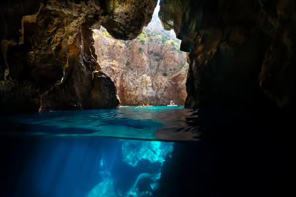 Vista di una grotta marina con acque turchesi e scogliere alte, vista dall'interno della grotta.
