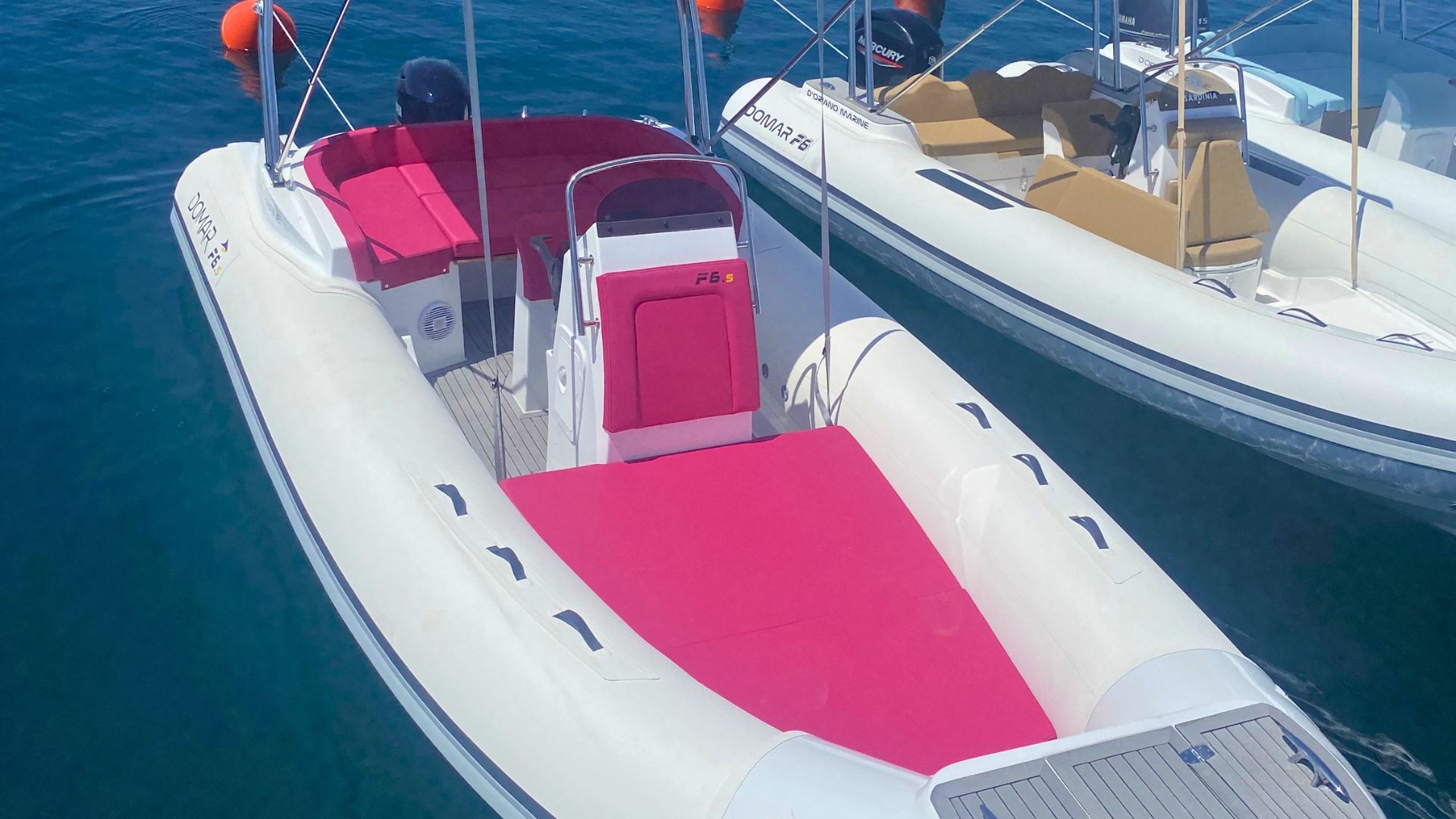 Two white rafts with red seats moored in water, one with a Mercury engine and the other with a Yamaha outboard motor