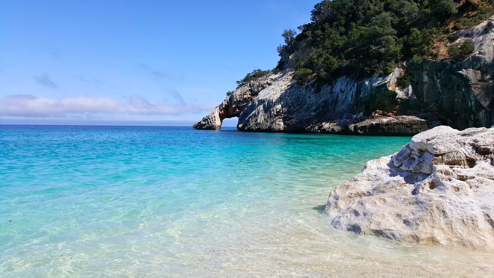 Image of a rocky coast with a natural arc and crystal clear sea