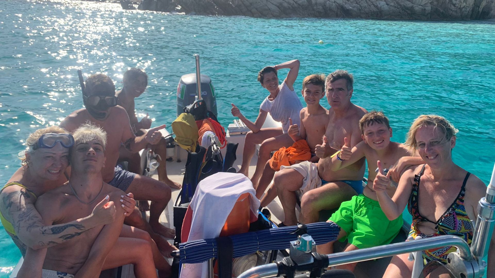 Un grupo de personas sonríe y disfruta de un recorrido en barco por el archipiélago de La Maddalena, con varias paradas para bucear