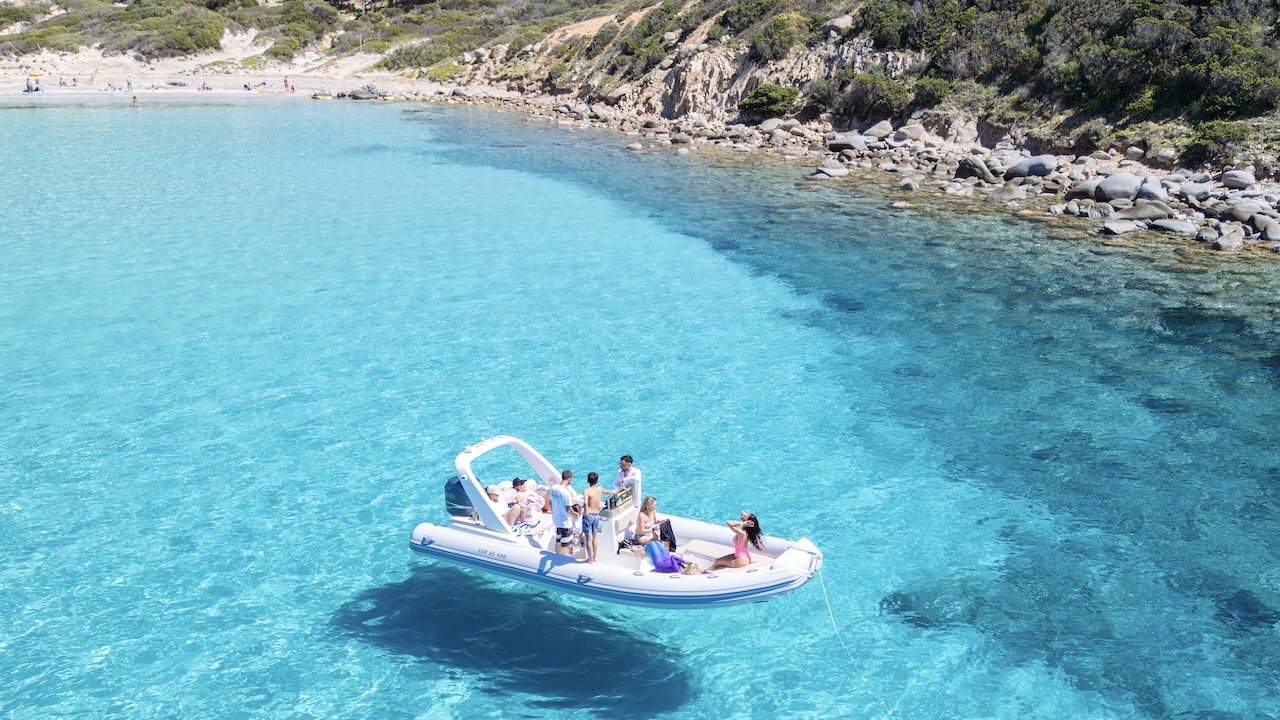 Un gruppo di persone in un gommone a vela in acqua cristallina con un'isola sullo sfondo