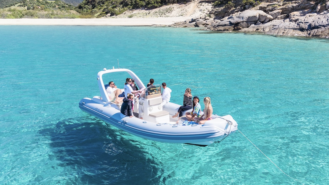Gruppo di persone in un gommone in acqua cristallina, sulla costa della Sardegna