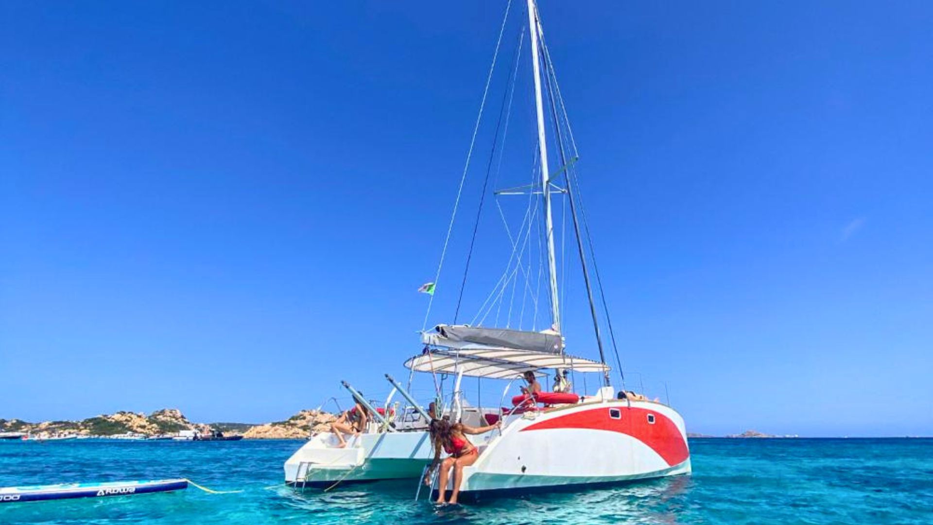 Photo d'un catamaran avec des personnes à bord dans une mer cristalline avec des îles en arrière-plan