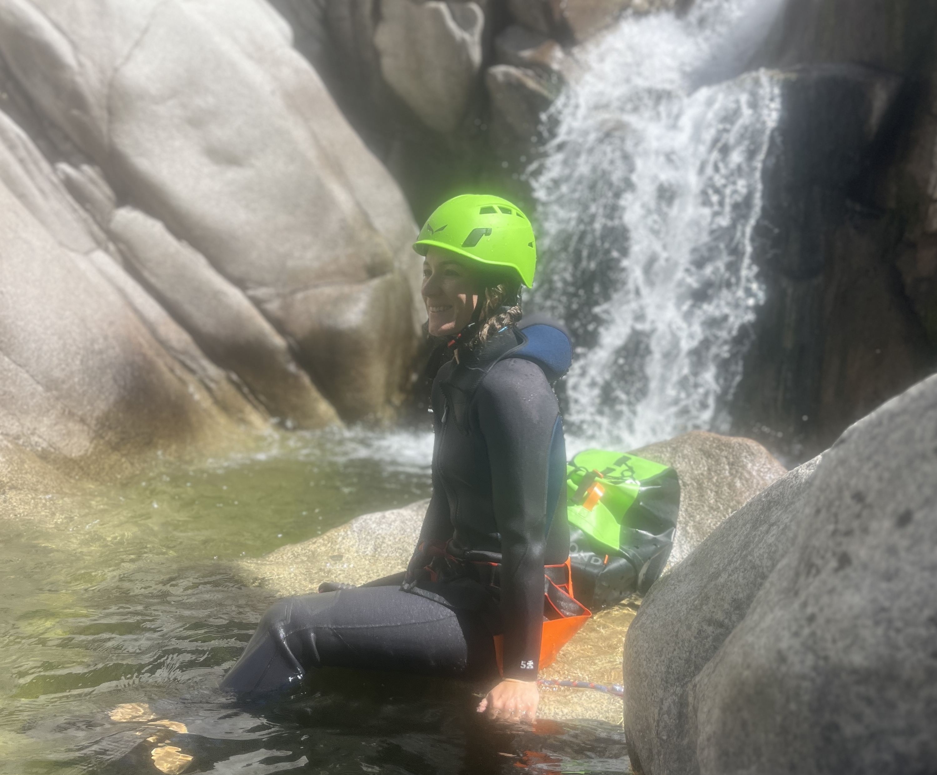 Una donna in costume da bagno e casco verde si gode una pausa in acqua tra le rocce