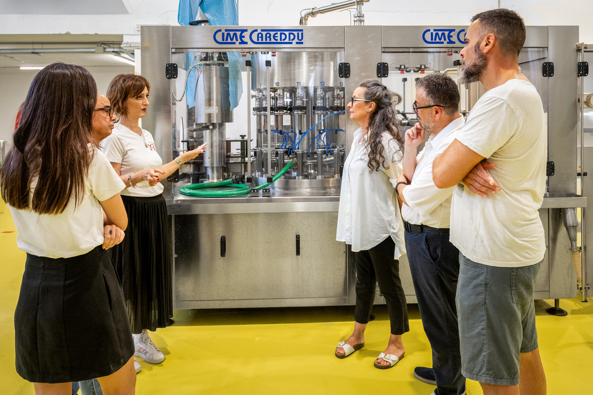 Gruppo di persone in visita guidata in un birrificio con macchinari e attrezzature per la produzione di birra artigianale