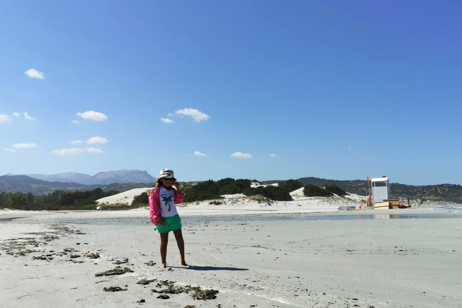 Une jeune femme en maillot de bain profite d'une journée ensoleillée sur la plage d'Orosei, entourée de dunes de sable blanc et de paysages à couper le souffle