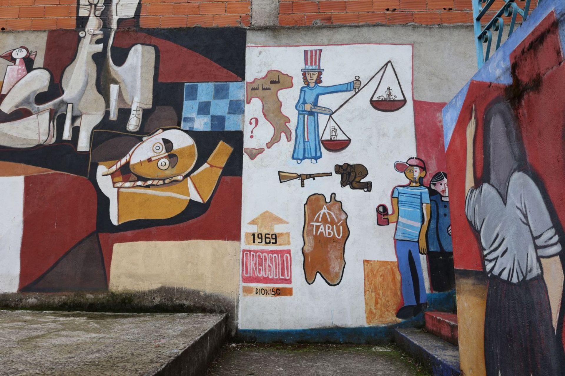 Mural di strada a Orgosolo con figure storiche, un uomo con bilancia e un altro che tiene un fucile