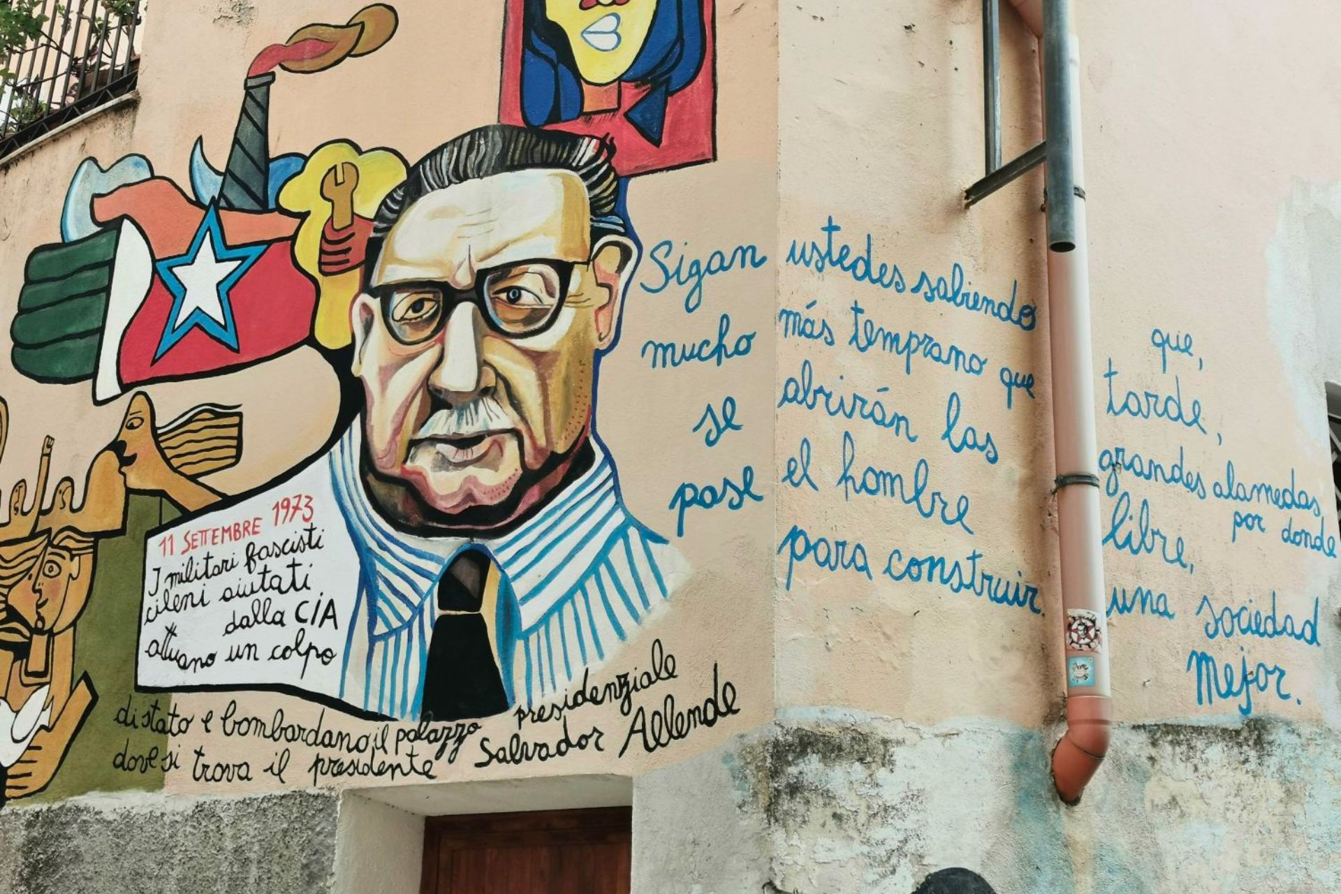 Mural artistico con figura maschile e simboli politici in una via cittadina