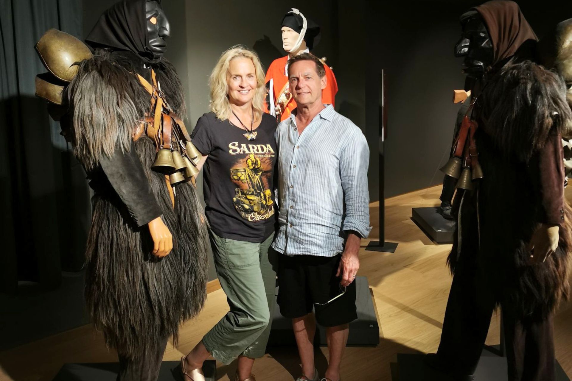Due persone in un museo con statue di Mamuthones e Issohadores in mostra