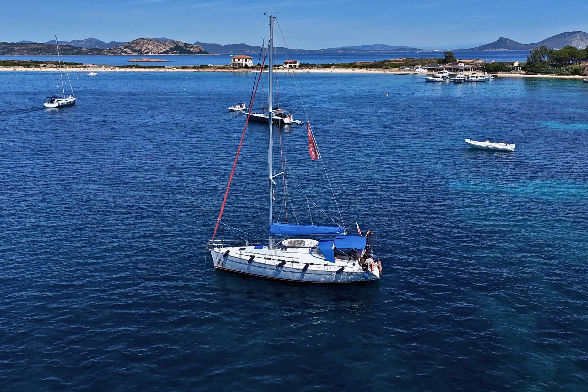 Imagen de un recorrido en velero con varios barcos en el agua y una playa al fondo