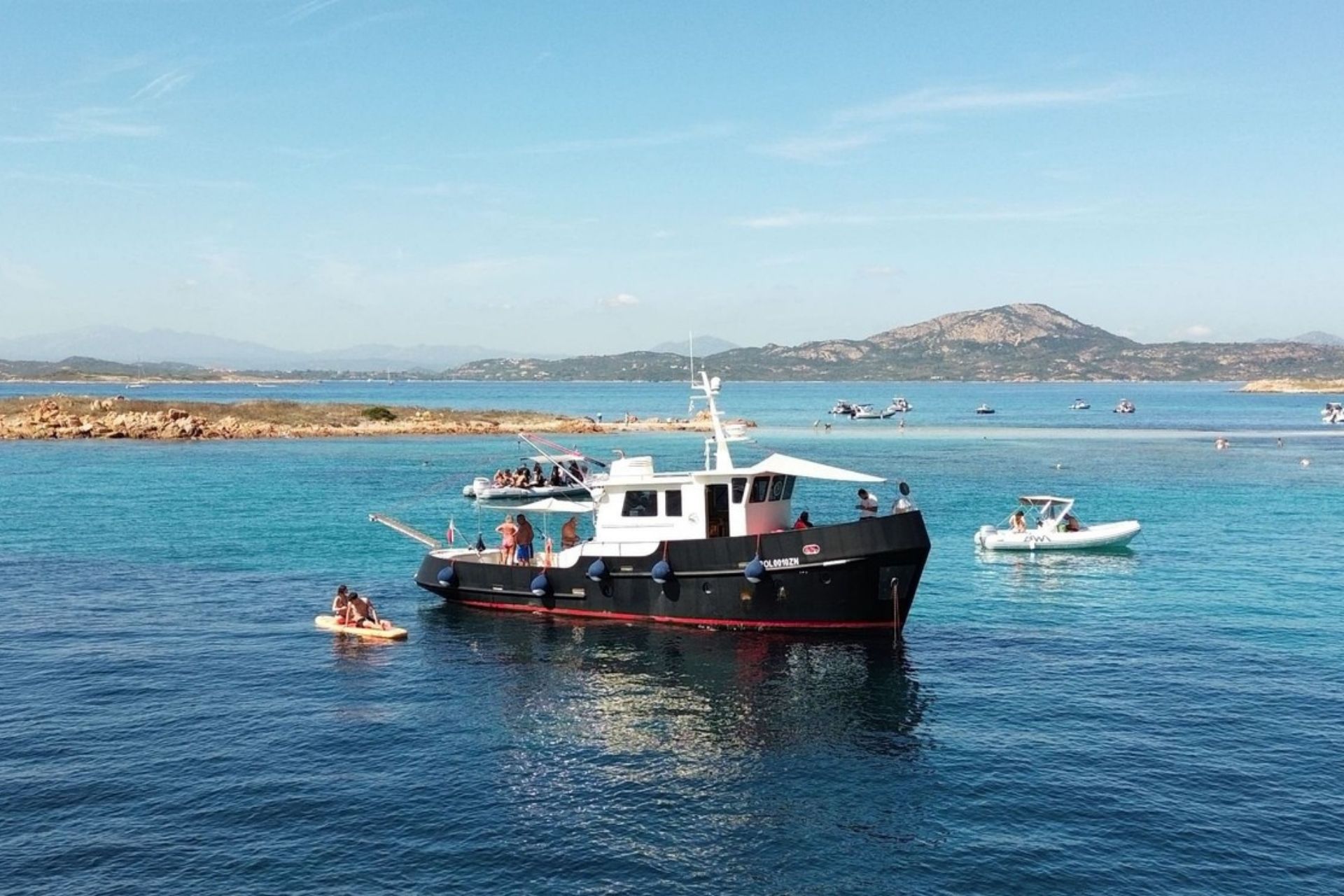 Bateau vintage avec des personnes à bord et d'autres bateaux en pleine mer avec des îles en arrière-plan
