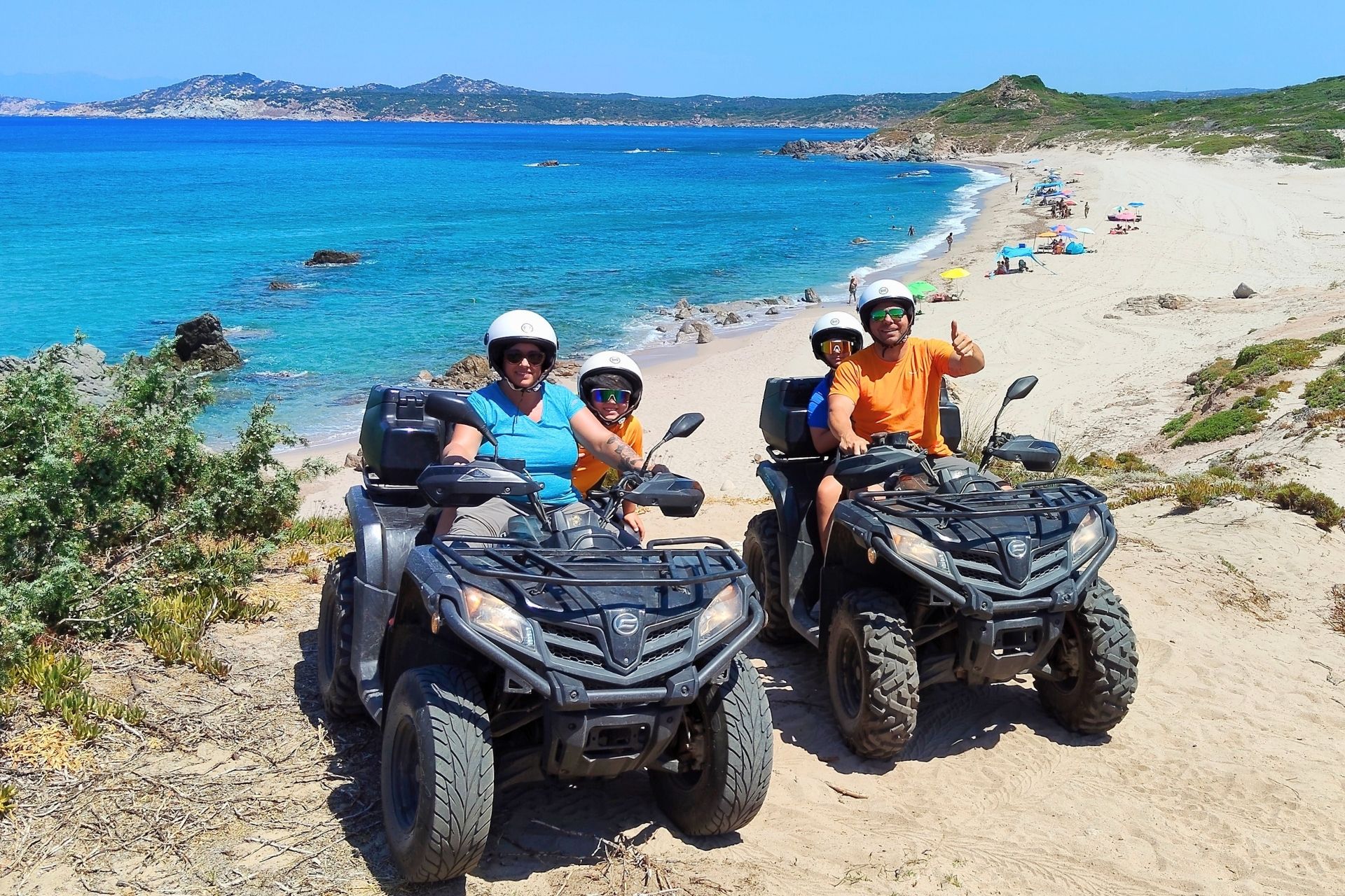 Tre persone su quad sulla spiaggia con il mare sullo sfondo